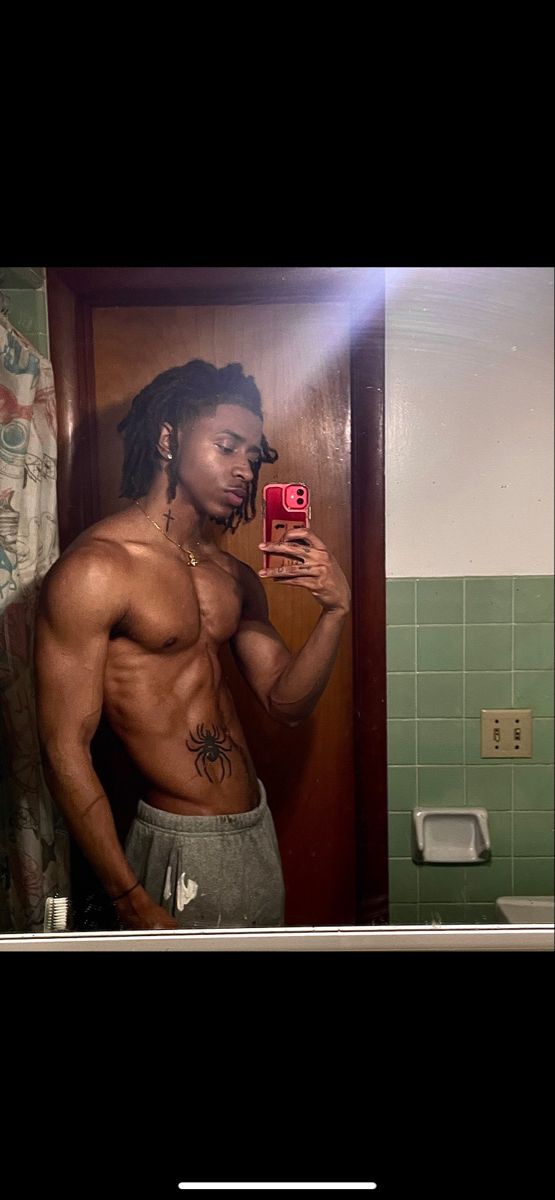 a shirtless man taking a selfie in a bathroom mirror with his cell phone