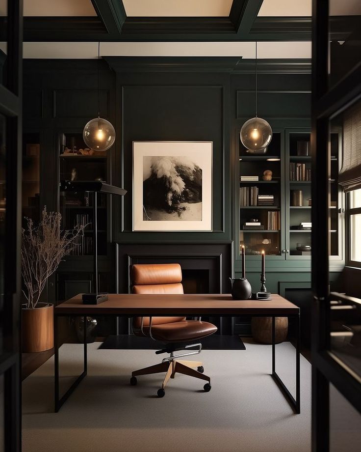an office with dark green walls and leather chair in the foreground, framed artwork on the wall