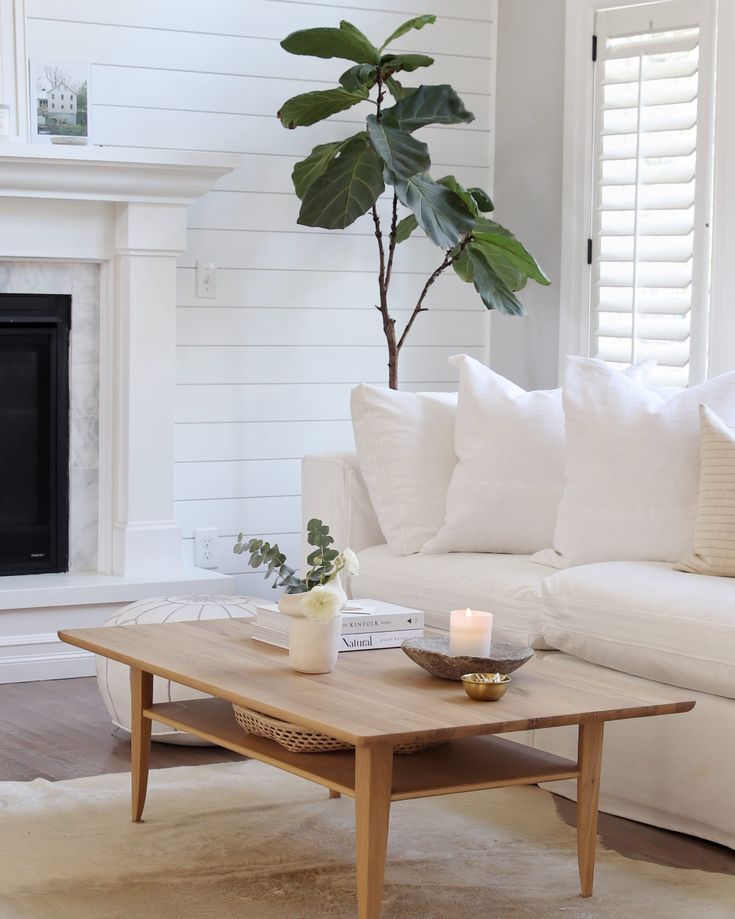 a living room with white couches and a coffee table in front of a fireplace