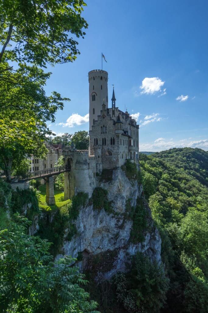 an old castle sitting on top of a cliff in the middle of trees and bushes
