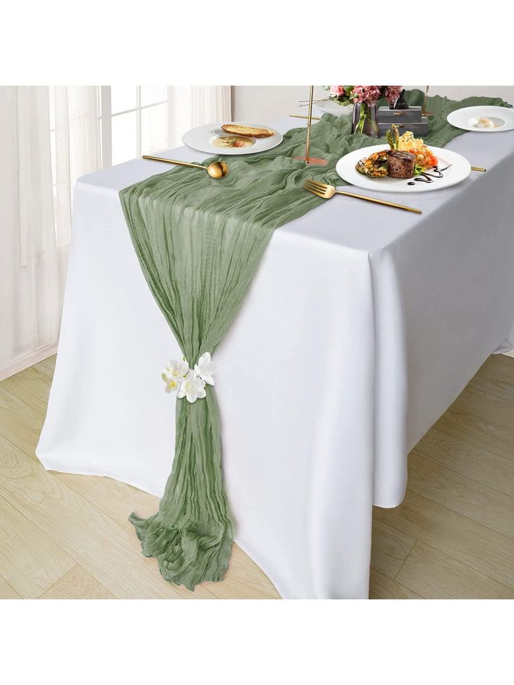 the table is set with green linens and place settings for two people to eat