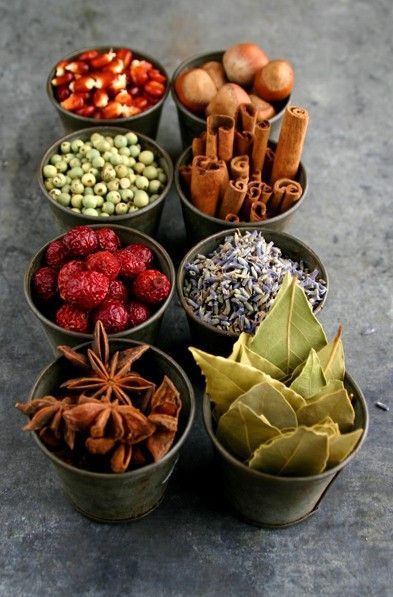 seven cups filled with different types of spices and herbs on a table next to each other