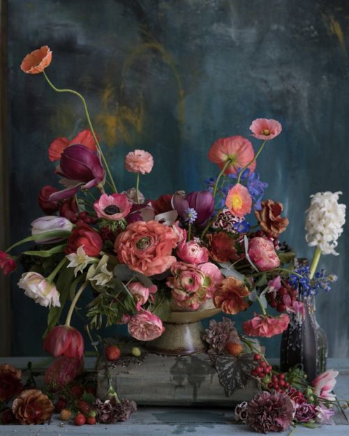 a vase filled with lots of colorful flowers on top of a table next to a painting