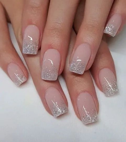 a woman's nails with white and silver glitter on them