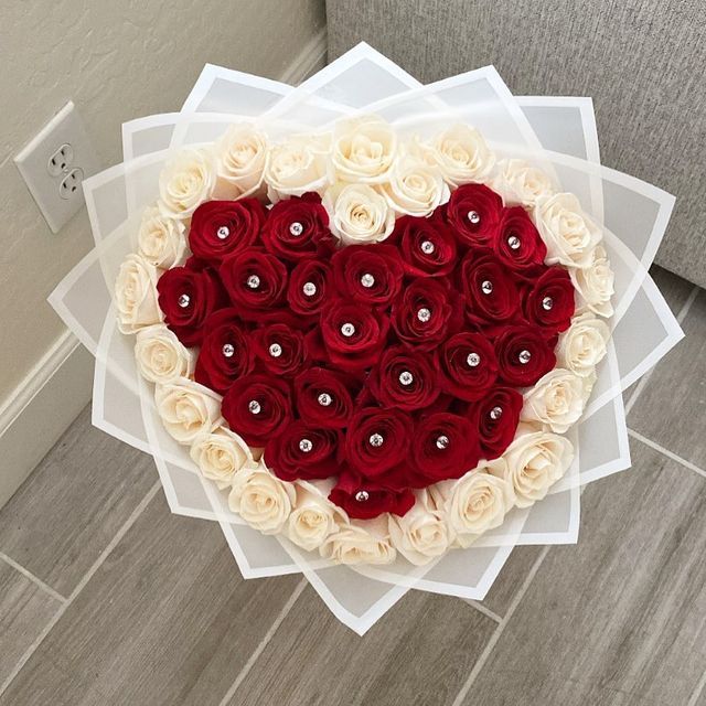 a heart shaped box filled with roses on top of a table next to a wall