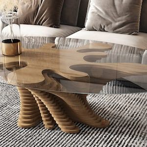 a glass table sitting on top of a rug in front of a couch with pillows
