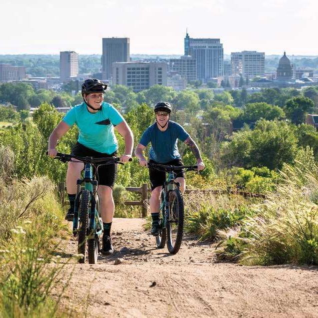 two people riding bikes on a dirt trail