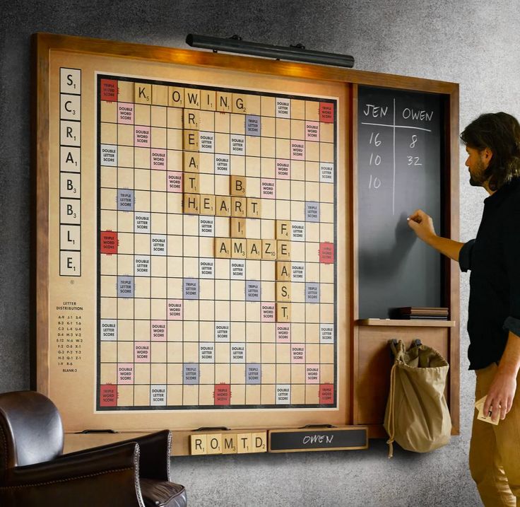 a man standing in front of a scrabble board