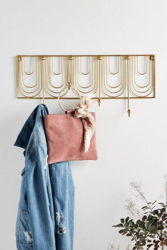 a coat rack and jacket hanger on a white wall with blue jeans hanging from it
