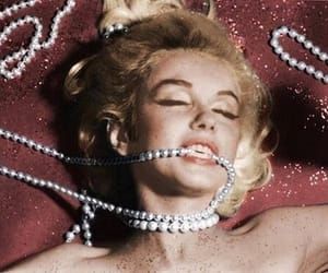 a woman laying on top of a red blanket covered in pearls and beads with her eyes closed