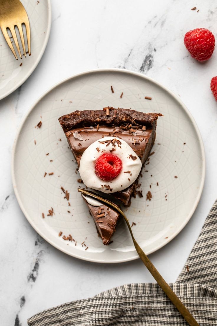 a piece of chocolate pie with whipped cream and raspberries