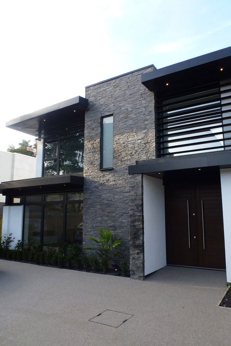 a modern house with black and white sidings on the front door, windows, and balconies