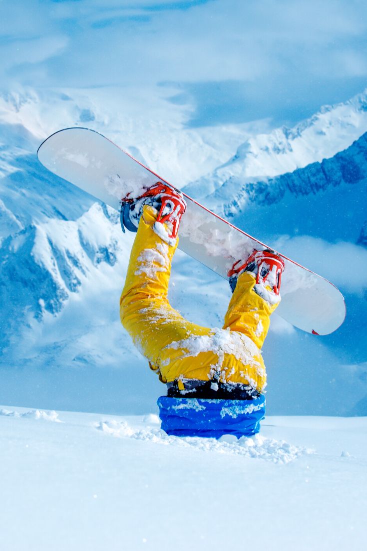 a snowboarder is upside down in the snow with his board on their feet