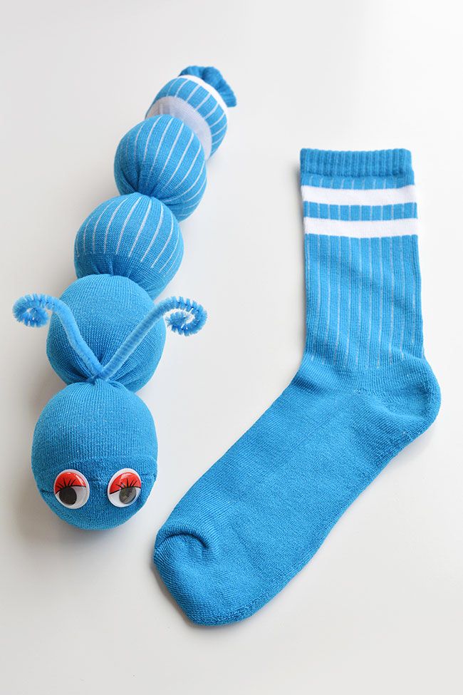 a blue sock with two balls attached to it next to a stuffed toy caterpillar