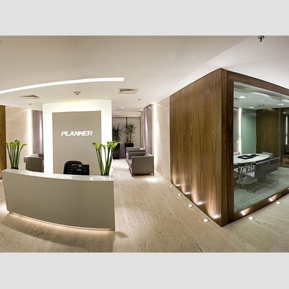 a modern office with wood paneling and white walls, along with planters on either side of the reception counter
