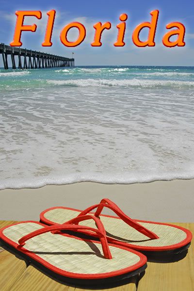 a pair of red flip flops sitting on top of a wooden floor next to the ocean
