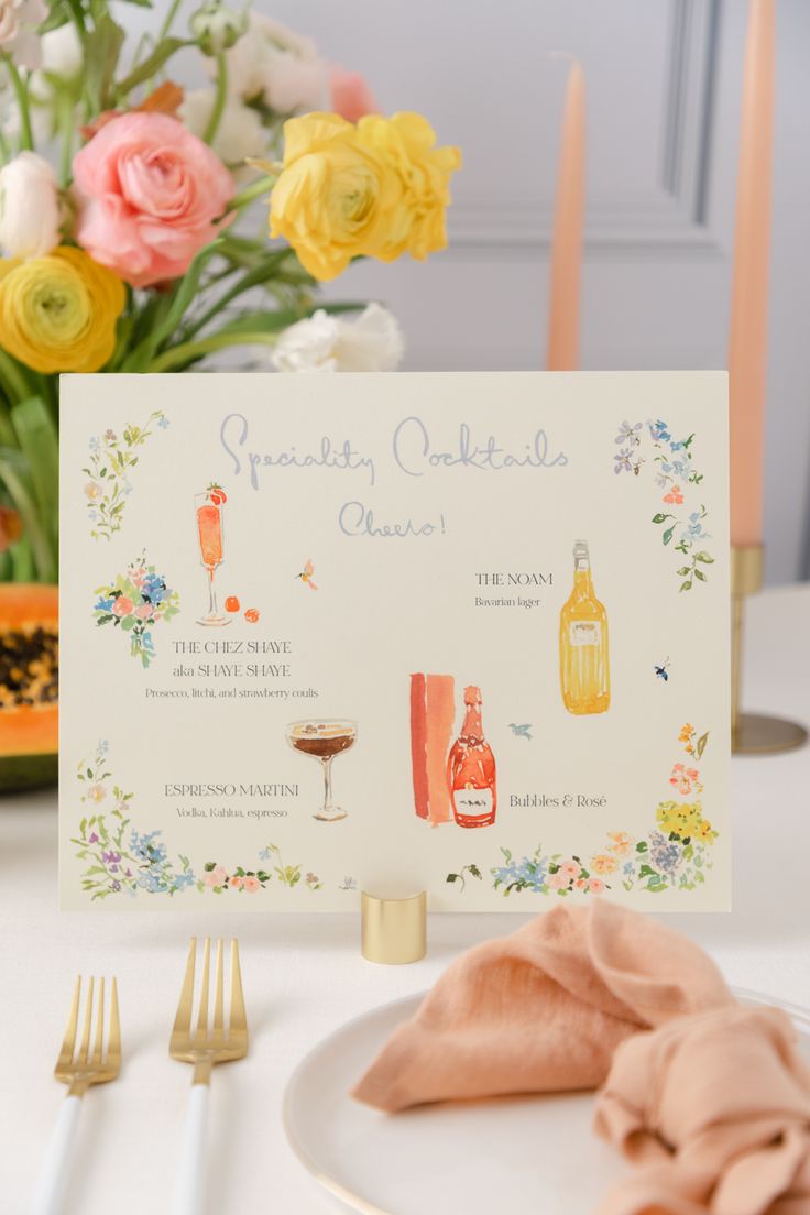 a place setting with flowers and wine on the table in front of it is a card that says special cocktails