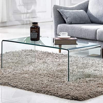 a glass coffee table sitting on top of a white rug in front of a couch