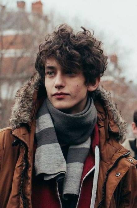 a young man wearing a brown jacket and scarf