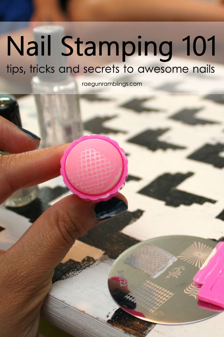 a hand holding a pink nail stamp on top of a checkered table with black and white tiles