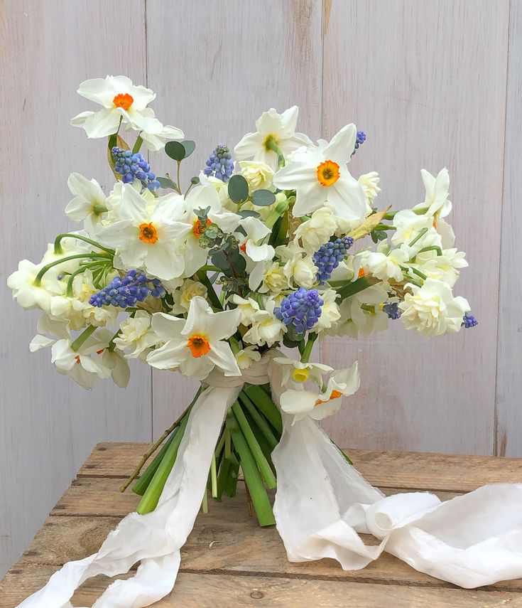 a bouquet of flowers sitting on top of a wooden table next to a white cloth