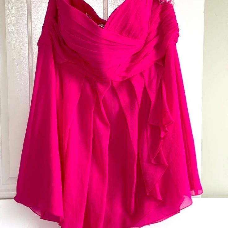 a bright pink dress hanging on a door