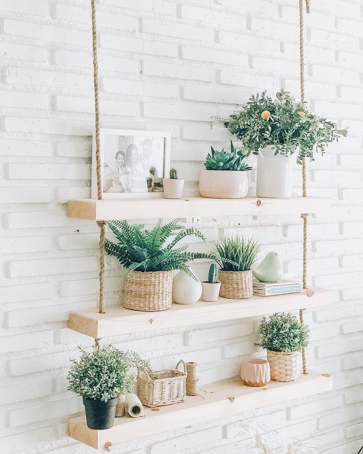 three shelves with plants on them against a white brick wall in a room that looks like it could be used as a planter