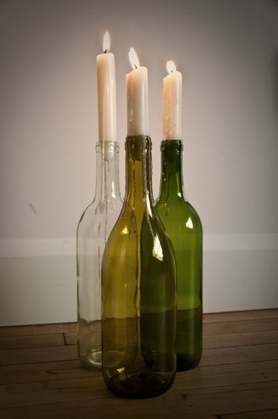 three wine bottles with candles in them sitting on a table
