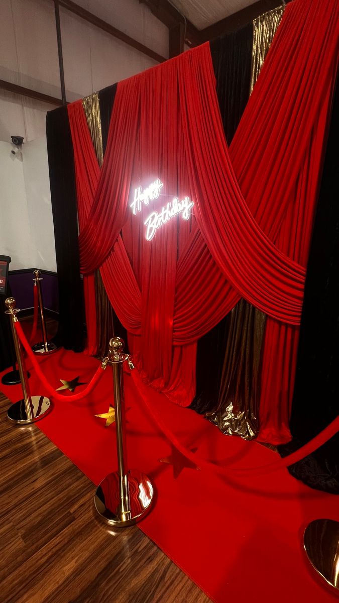 a red carpeted room with black and white walls, gold barriers and metal poles