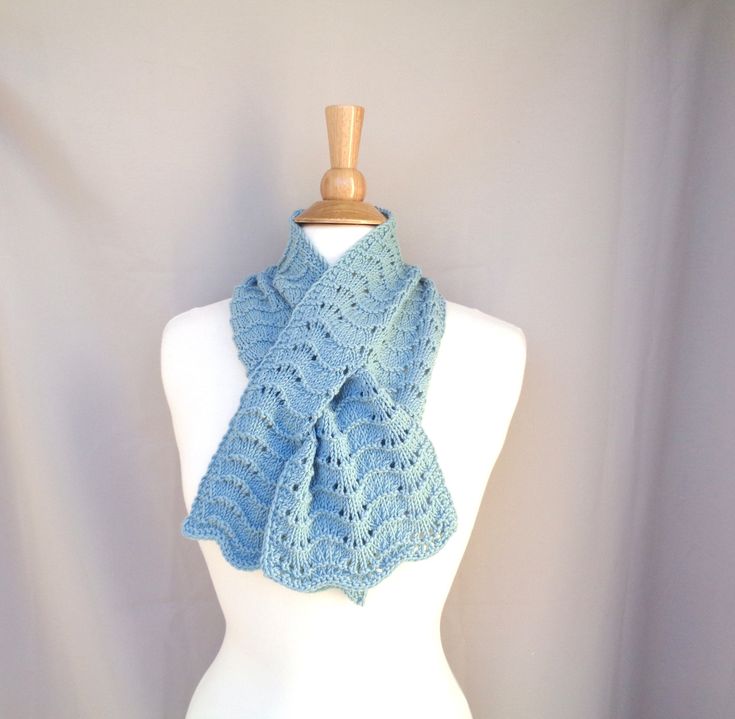 a white mannequin wearing a blue crocheted scarf on top of it