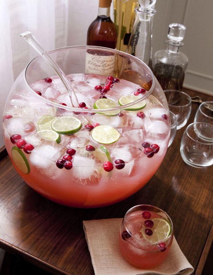 a pitcher filled with ice and cranberries on top of a table next to glasses