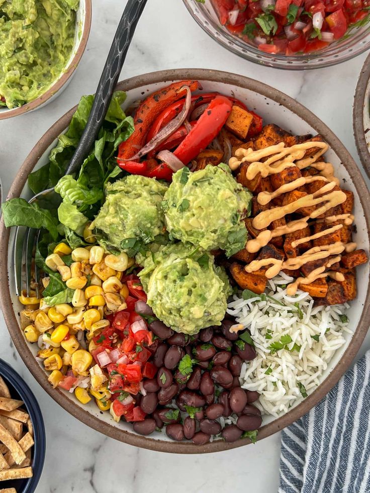 a bowl filled with different types of food and some guacamole on the side