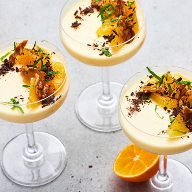 three martinis with orange slices and garnish on the rim, sitting next to each other