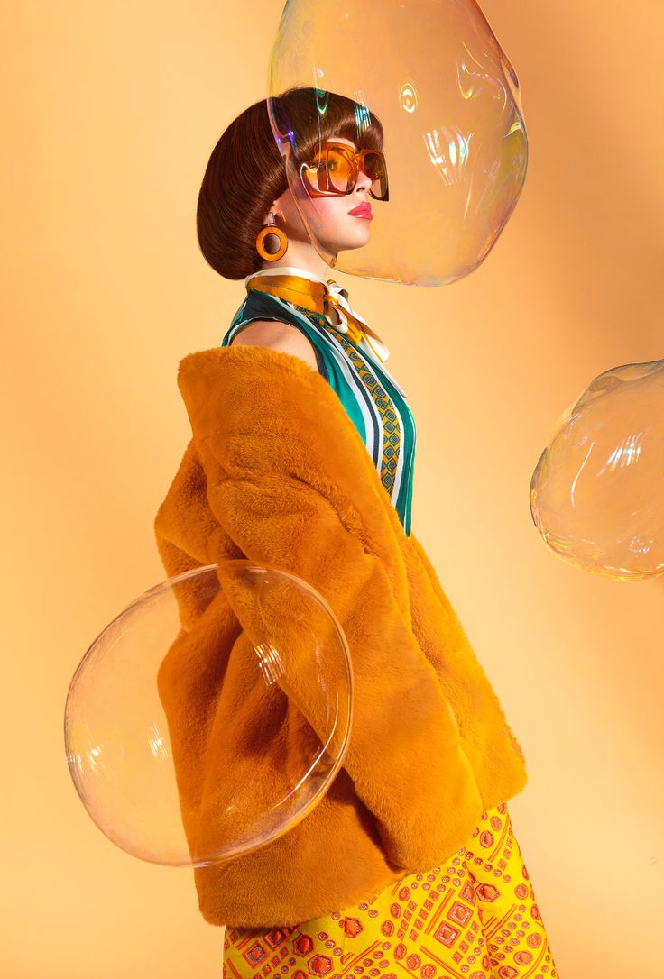 a woman with large bubbles on her head is holding a glass bowl in front of her face