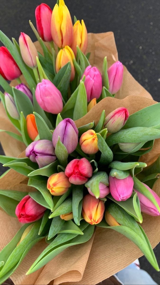 a bouquet of tulips is wrapped in brown paper