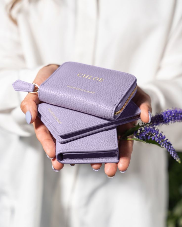 a person holding three purple books in their hands