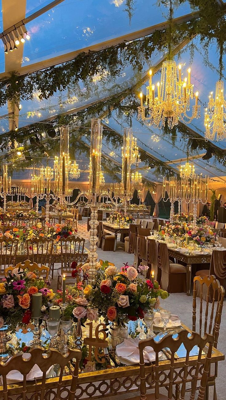 a large tent with tables and chairs set up for a formal dinner or function in the evening