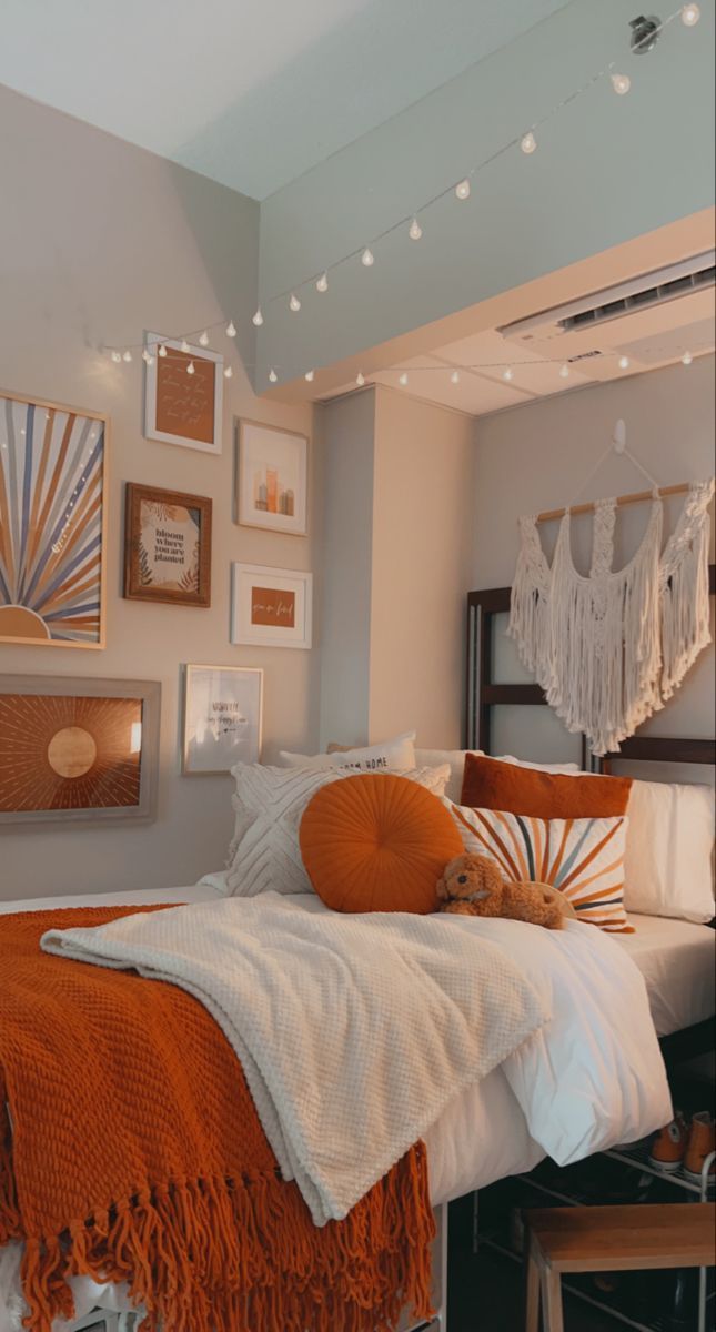 an orange and white bedroom with pictures on the wall above the bed, hanging art