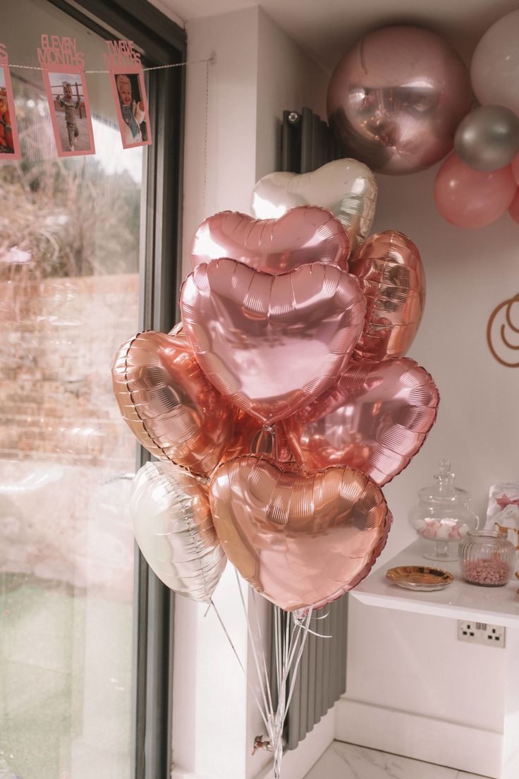 a bunch of balloons that are in the shape of hearts on a window sill