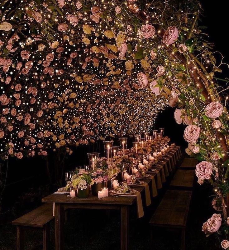 a long table with candles and flowers on it is set up for an outdoor dinner