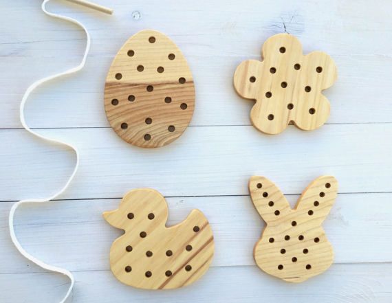 four wooden easter bunnies with holes in them on a white wood surface next to a string