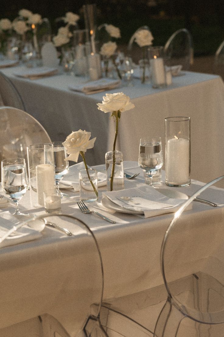 the table is set with white flowers and silverware