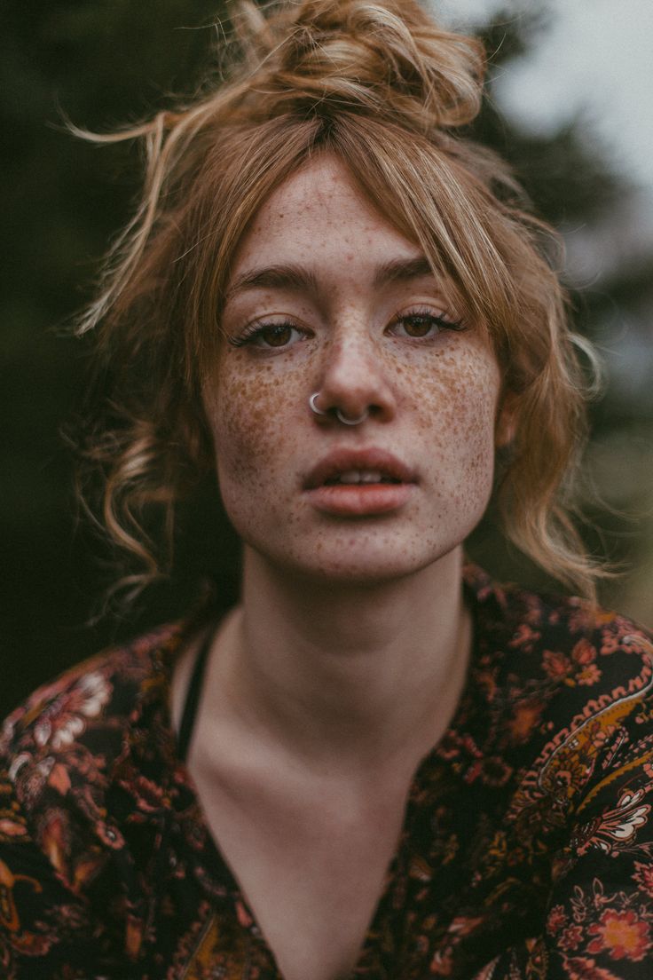 a woman with freckles on her face is staring at the camera while she has freckled hair