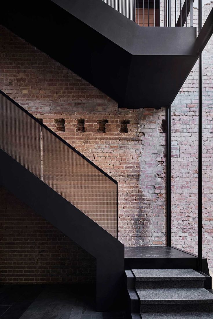 the stairs are black and there is a brick wall in the background with two balconies on each side