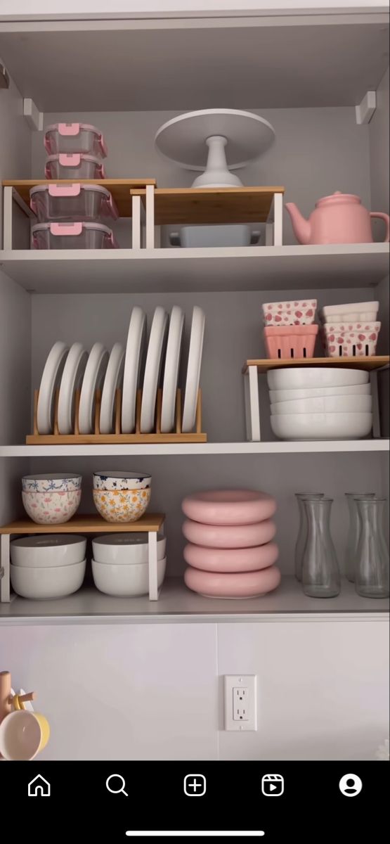 the shelves are filled with dishes and plates in pink, white, and grey colors