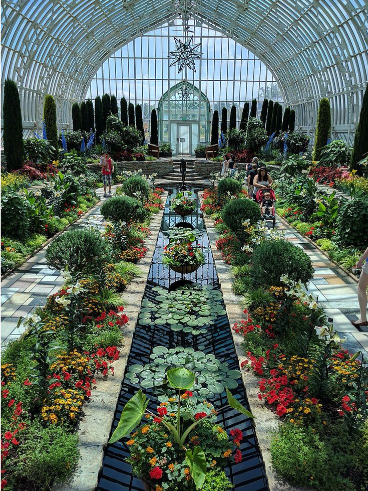 the inside of a large greenhouse with many plants and flowers in it's center