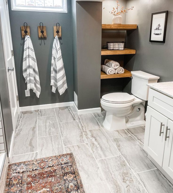 a bathroom with two towels hanging on the wall and a rug in front of it