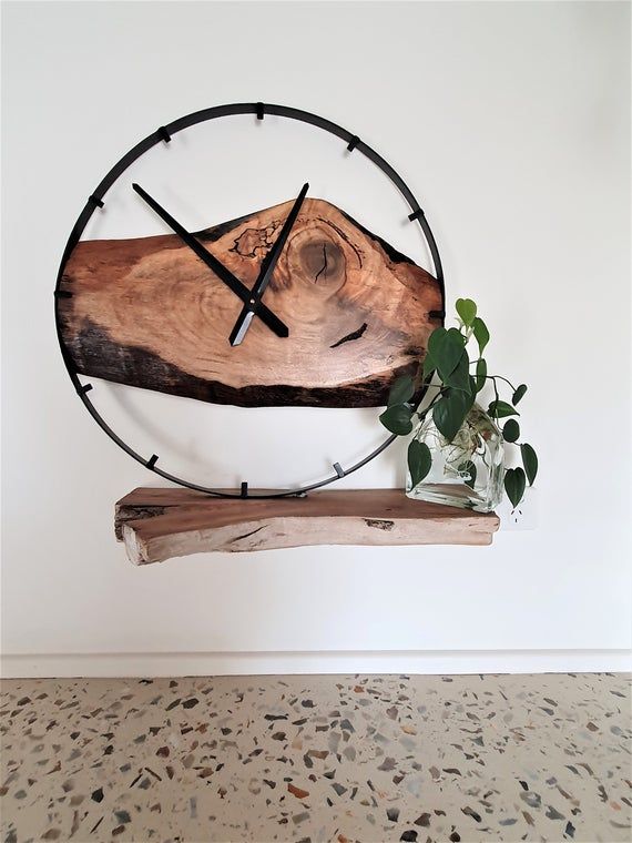 a clock that is on the side of a wall next to a potted plant
