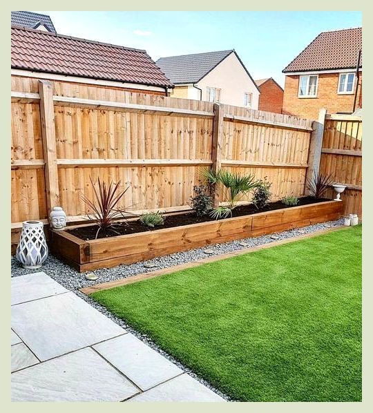 a backyard with grass and wooden fenced in area next to the yard is an artificial lawn