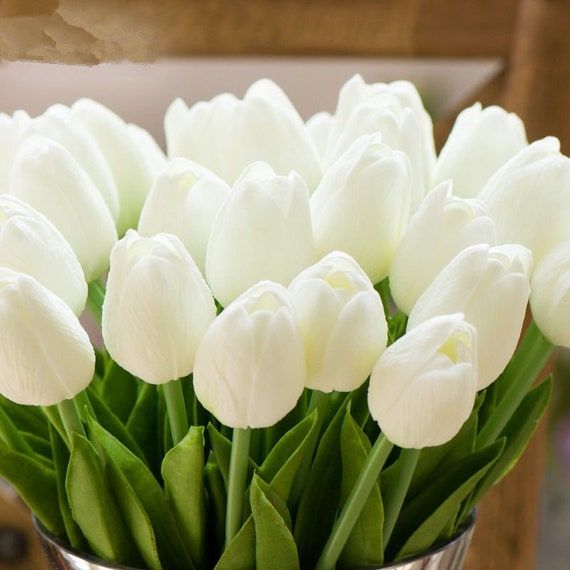 a bunch of white tulips are in a vase